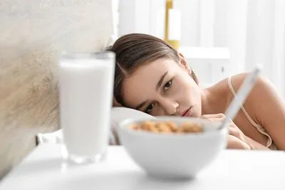 Woman with eating disorder looking at plate of food unwilling to eat