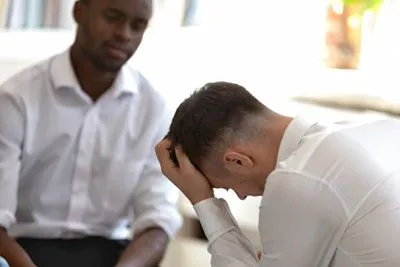 Man in therapy session processing emotional trauma with a mental health professional.