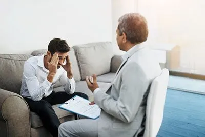 Man suffering from a headache in a counseling session