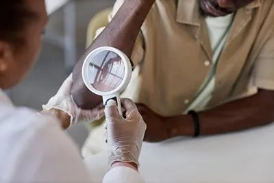 Dermatologist examining patient’s skin for early signs of melanoma or other skin cancers