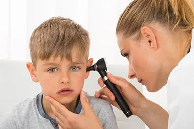 Pediatrician using otoscope to check child’s ear infection