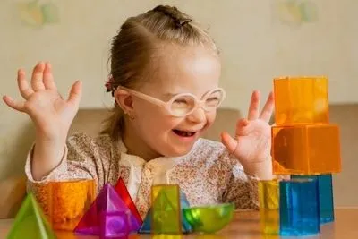 Young child with down syndrome feeling happy in puzzle