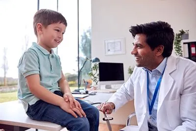 Pediatrician conducting reflex assessment in child’s sports checkup