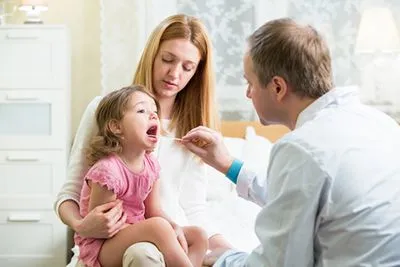 Pediatrician evaluating a sick child during a clinic visit