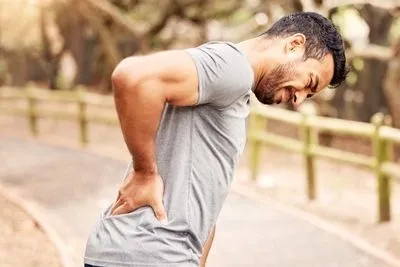 Man-holding-his-back-heavily-in-pain-outdoor.