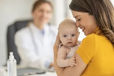 Mother holding newborn during consultation with pediatrician