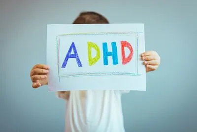 Colorful crayon drawing of the word ADHD held by a child for educational concept