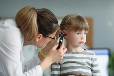 Child receiving ear examination for infection by pediatrician