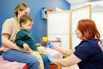 Pediatrician performing reflex test to monitor neurological development in young child
