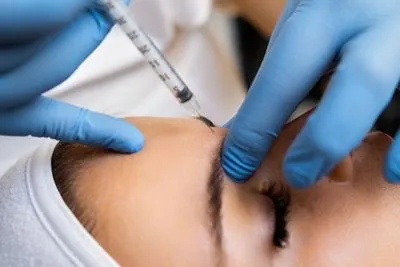 Woman receiving Botox injections on her forehead to reduce wrinkles