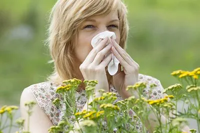 Woman sneeze outdoor with the pollen in her face