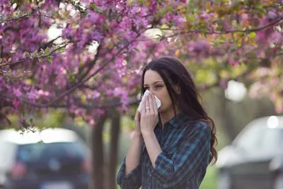 Woman sneezing because of seasonal pollen allergies