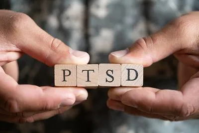 Military veteran using wooden blocks to spell out PTSD, highlighting post-traumatic stress disorder