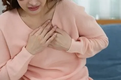 Woman holding her chest in pain indoor