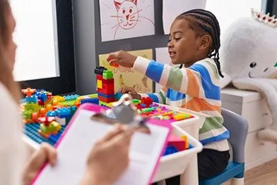 Child using toys and games in structured play therapy session with professional
