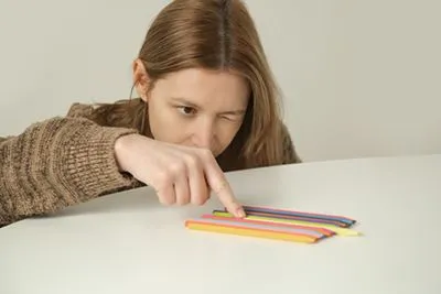 Obsessive-compulsive woman arranging pencils neatly on a table