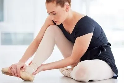 Ballet dancer holding her foot in pain