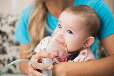 Baby using a nebulizer mask for bronchiolitis treatment