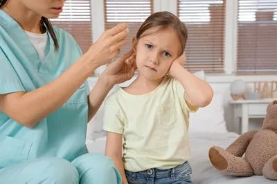Little girl visiting pediatrician for ear infection treatment