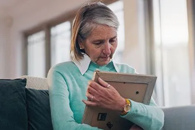 Sad woman holding photograph in memory of loved one
