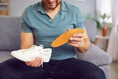 Male patient inserting custom orthotic insoles into footwear