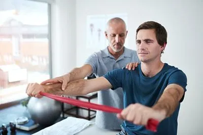 Male client using a resistance band during physical therapy