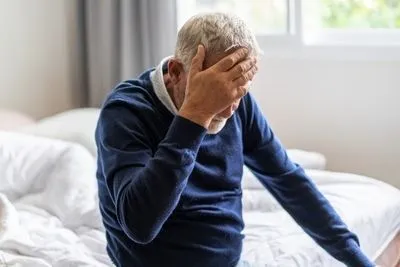 Senior man in headache on bed