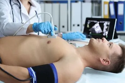 Cardiologist performing echocardiography on male patient for cardiac evaluation