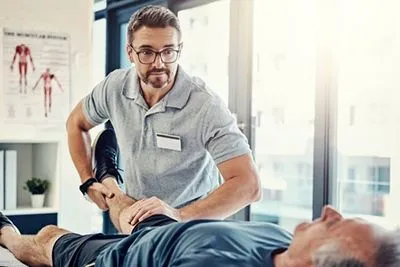 Chiropractor providing knee pain treatment for a senior man