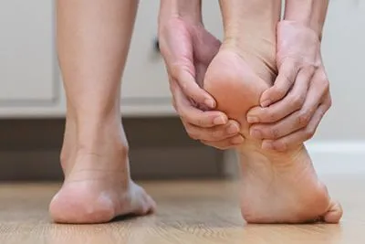 Individual suffering from heel pain, clutching affected area