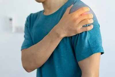 Man-holding-his-shoulder-in-pain-with-navy-blue-shirt.