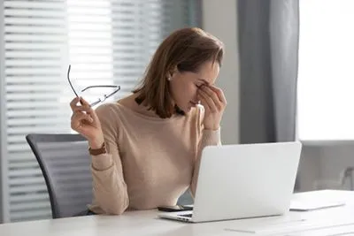 Woman suffering from dry eye infront of laptop