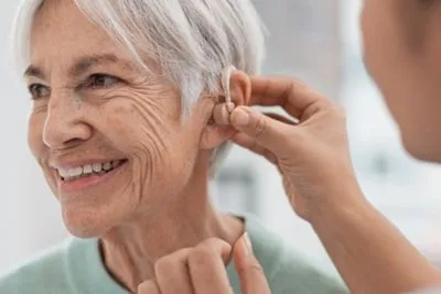 Doctor assisting senior woman with hearing aid fitting