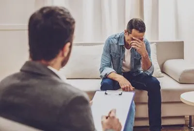 Male patient experiencing trauma flashbacks in therapy session