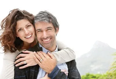 couple smiling nice teeth hugging outdoors, best dentist Millbrae, CA dental bridge