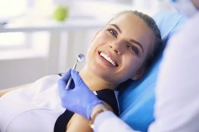 blond teen girl smiling sitting in dental chairgetting oral exam from dentist Philadelphia, PA