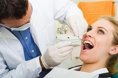 dentist checking woman's mouth with dental tools, performing periodontal exam, periodontist Brookline, MA