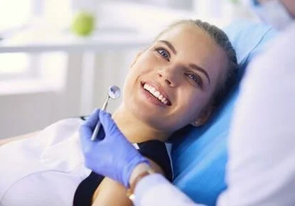 blond woman smiling sitting in exam chair wearing dental bib looking up at hygienist, teeth cleaning Windsor Locks, CT dentist