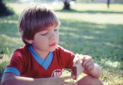 young boy eating a sandwich in a park