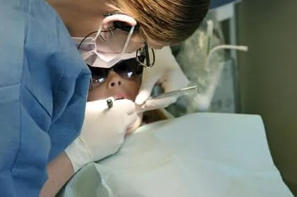 female dental assistant cleaning female patient's teeth, family dentist Columbia, MO