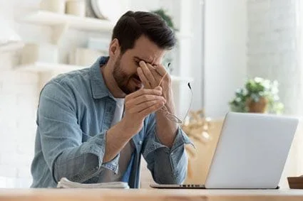 Man rubbing eyes at computer