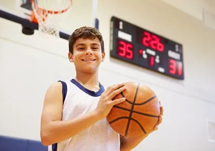 young boy holding basketball on court, athletic mouthguards Brookline, MA dentist