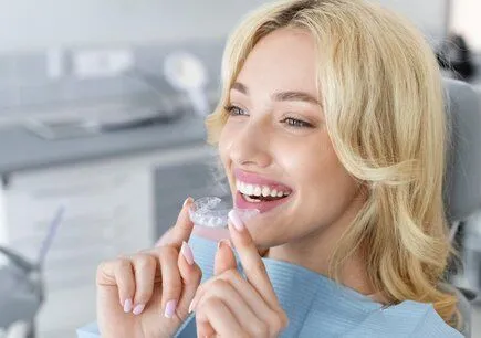 blond woman in dental exam room placing clear aligner tray in mouth, clear braces Phoenix, AZ Clear Correct