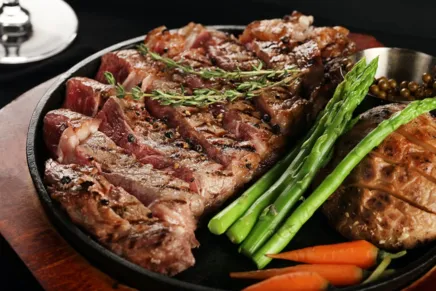 A dish of steak with asparagus and carrots. 
