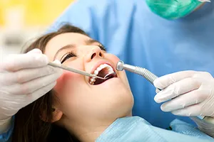 woman smiling in dental chair with dentist hands and tools in her mouth
