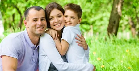 young parents outside hugging boy by trees, kids dentist Frederick, MD pediatric dentistry