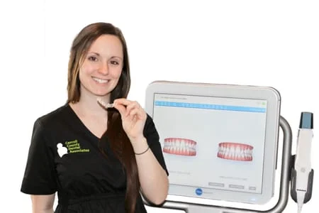 female Carroll County Dental Associates staff member holding Invisalign aligner next to iTero machine, Westminster, MD dentist