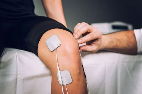 Electrical stimulation pads being placed on a patient's knee