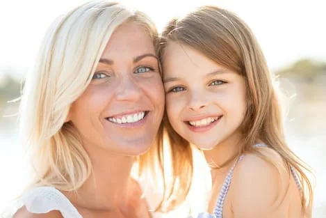 blond woman smiling holding little girl Lee's Summit, MO family dentist