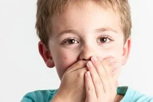 young boy covering his mouth afraid to go to the dentist